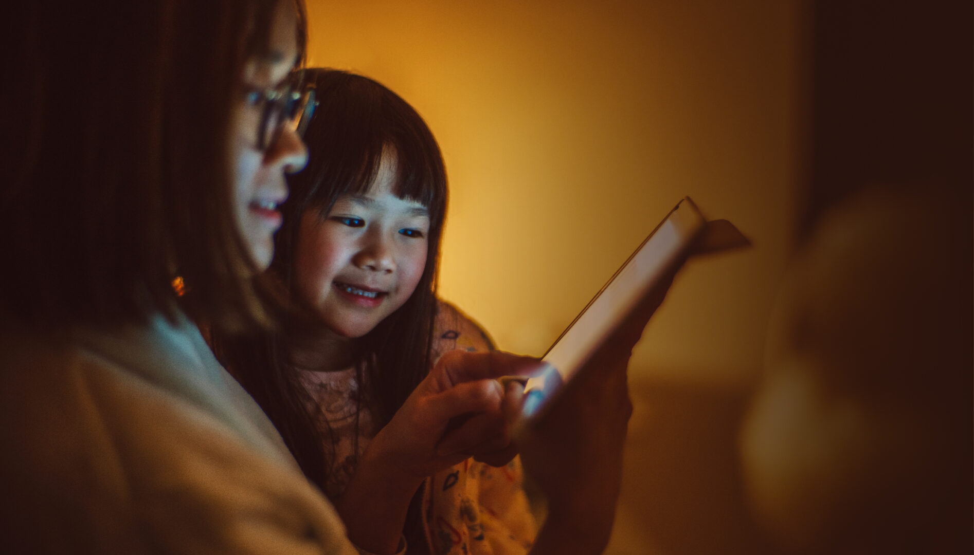 Mother and child using a tablet in a warmly lit room