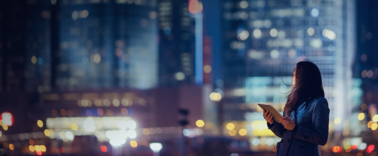 A woman on a tablet in front of a cityscape