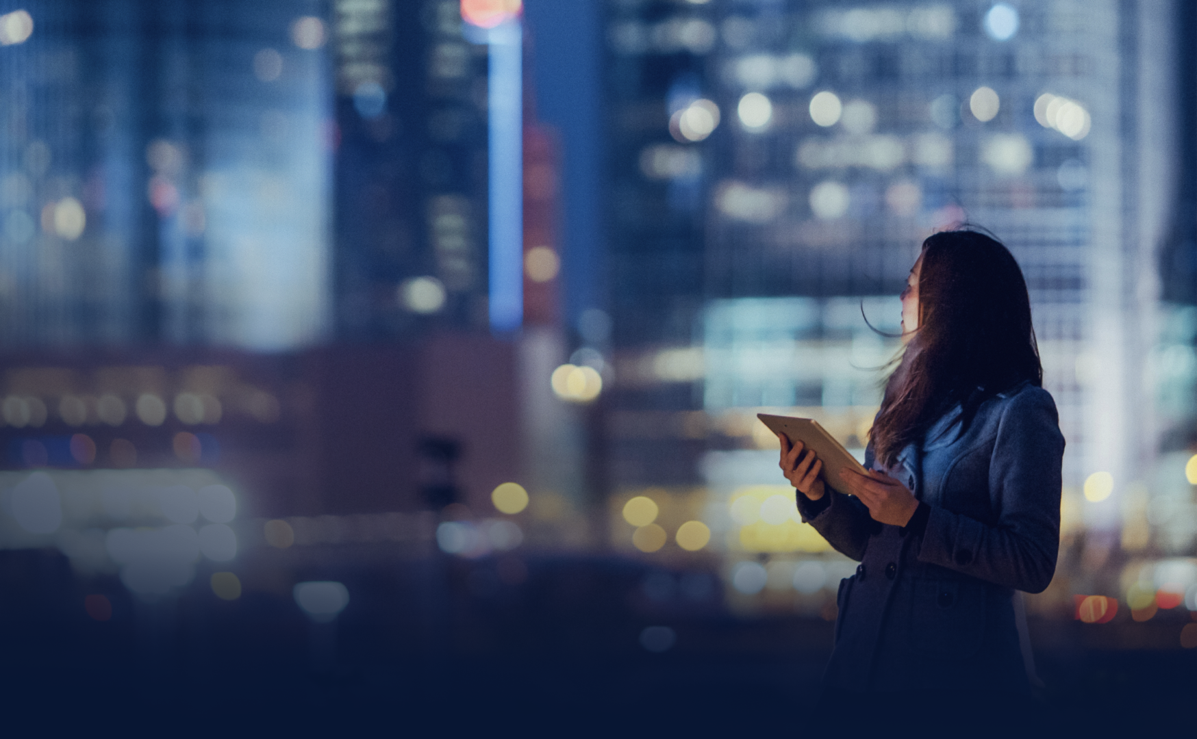Woman on tablet in a well lit city